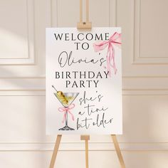 a welcome sign for a birthday party with a martini in the glass and pink ribbon