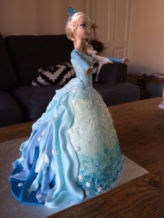 there is a cake that looks like a princess in blue dress on top of a table