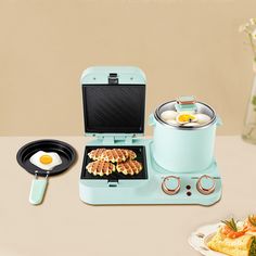 an electric waffle maker with eggs on top and other food items around it, sitting on a table