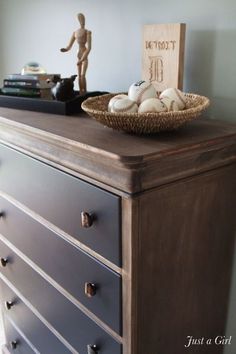 a wooden sign sitting on top of a dresser next to a basket filled with eggs