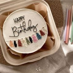 a birthday cake with the words happy birthday written on it in black letters and tassels