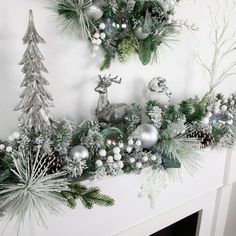 a fireplace mantel decorated with silver and white christmas decorations