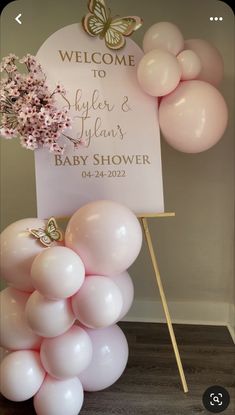 a baby shower sign and balloons in the shape of a bunch of flowers with a butterfly on top