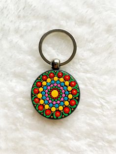 a keychain with a colorful design on it sitting on a white fur surface