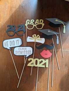 graduation party photo booth props on a wooden table in front of a class room door