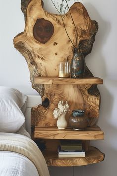 a wooden shelf sitting on top of a bed next to a vase and bookcase