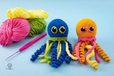 two crocheted octopuses sitting next to each other with yarn in the background