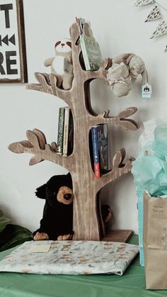 a stuffed animal is sitting in front of a wooden tree with books on it's shelf