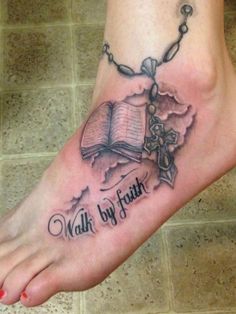 a tattoo on the foot of a person with an open book and rosary hanging from it