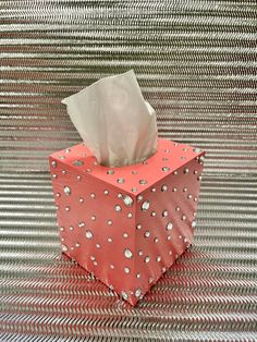 a tissue box sitting on top of a metal table covered in polka dotty paper