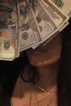 a woman is hiding her face behind stacks of money