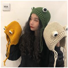 a woman holding two knitted hats in front of her face