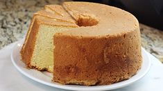 a bundt cake on a white plate with a slice taken out of it and sitting on a marble counter top