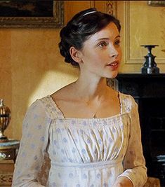 a woman in a white dress standing next to a stove