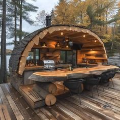 an outdoor kitchen is built into the side of a wooden deck with chairs around it