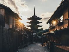 the sun shines brightly through the clouds over an alley way with buildings and pagodas