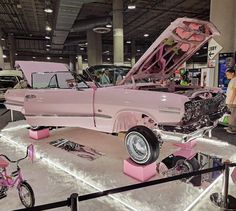 an old pink car is on display in a showroom