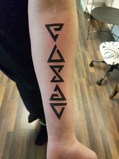 a person with a tattoo on their arm that has an arrow and letters in black ink