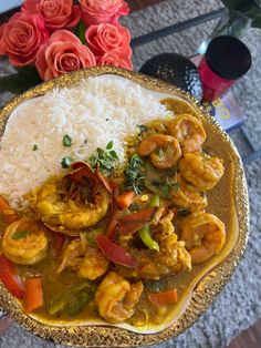 a plate with rice, shrimp and vegetables on it next to some flowers in a vase