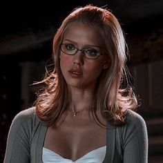 a woman with glasses is standing in the dark