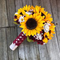 a bridal bouquet with sunflowers and baby's breath on a wooden floor