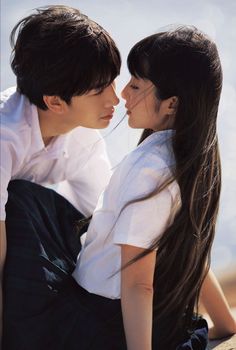 a man and woman sitting next to each other with long hair on their backs kissing