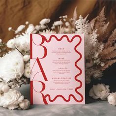 a red and white wedding menu on a table with flowers