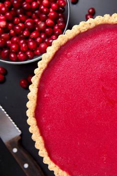 a pie with cranberry sauce on it next to bowls of cranberries