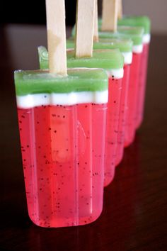 four popsicles with toothpicks sticking out of them sitting on a wooden table