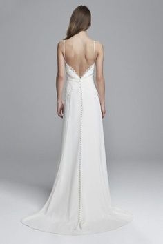 the back of a woman's white wedding dress with beaded details on it