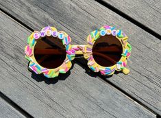 Step into a sprinkle-filled wonderland with these enchanting first birthday sunglasses! Crafted for tiny trendsetters, these frames dazzle in a delightful candy-coated pink or cheerful sky blue. The rims are generously dusted with colorful fake sprinkles, giving them a whimsically sweet appearance that mimics a frosted birthday cake. These glasses aren't just a party accessory; they're a pinch of joy and a sprinkle of fun for the big 'One'! **ITEM DETAILS** *You can pick from Color Letters, Gold Multicolor Plastic Sunglasses For Birthday, Playful Multicolor Sunglasses For Birthday, Fun Sunglasses With Tinted Lenses For Birthday, Playful Tinted Sunglasses For Birthday, Playful Sunglasses With Tinted Lenses, Pastel Sunglasses, Birthday Sunglasses, Novelty Glasses, Fake Sprinkles