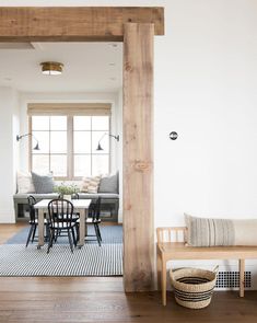 an open living room and dining area with wood beams in the ceiling, hardwood flooring, and white walls