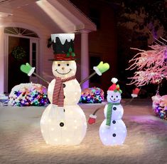 two lighted snowmen in front of a house