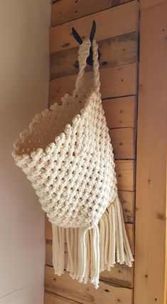 a white crocheted bag hanging on a wooden wall