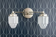 two lights on the wall in front of a blue and white tiled wall with geometric design