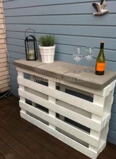 an outdoor bar made out of pallets with wine glasses and a bottle on top