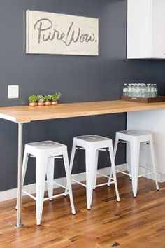 three stools in front of a table with plants on it and a sign that says pure wins