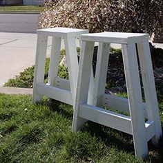 two white wooden benches sitting in the grass