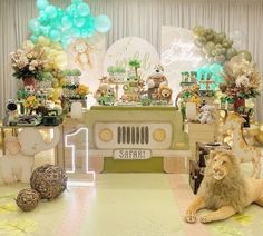 a lion laying on the floor in front of a table with balloons and other decorations