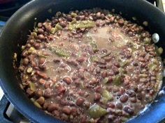 beans and onions cooking in a blue pan on the stove top next to an apple