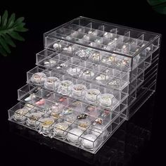 a large clear box filled with lots of different types of jewelry and bracelets on top of a black surface