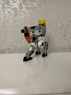 a lego robot with a yellow helmet on it's head sitting on a table