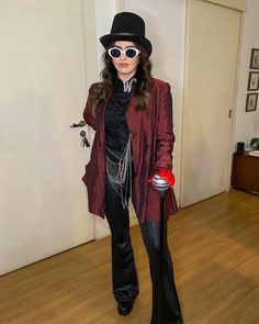 a woman dressed in black and red poses for the camera while holding a canister