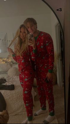 a man and woman in matching christmas pajamas taking a selfie