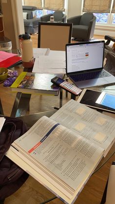 an open book sitting on top of a table next to a laptop computer and tablet