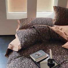 a bed with two pillows and a book on it next to a window sill