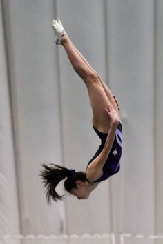 a woman jumping in the air on top of a trampoline