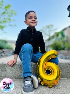 a young boy sitting on the steps with his number six balloon in front of him