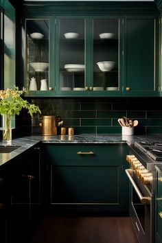 a kitchen with dark green cabinets and gold trim on the counter tops, along with brass pulls