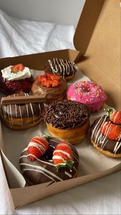 a box filled with assorted donuts and strawberries on top of each other